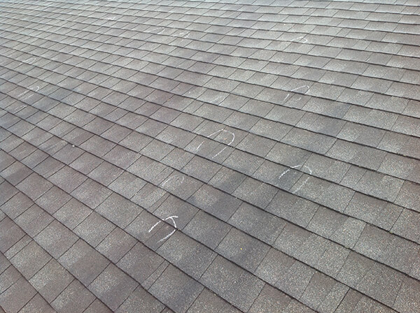 hail damaged roof with insurance adjuster marks